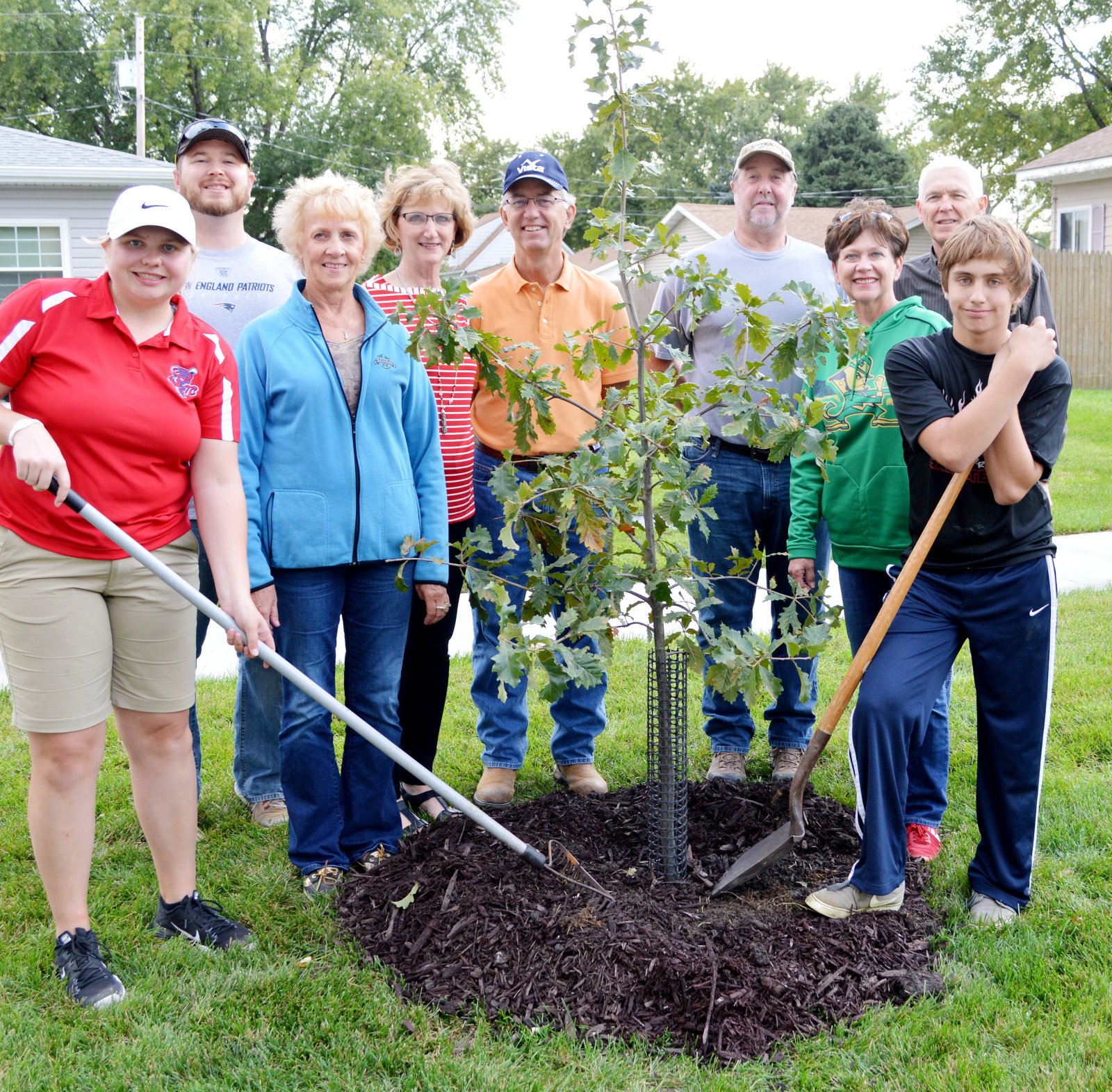 Tree planters standing by a recently planted oak tree. 