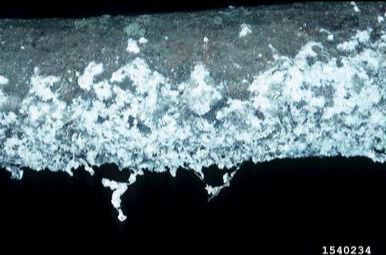 White crystalline deposits forming on a dark surface against a black background.