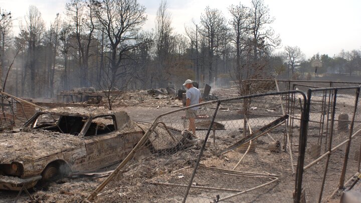 Homeowner walks through the aftermath of a wildfire. 