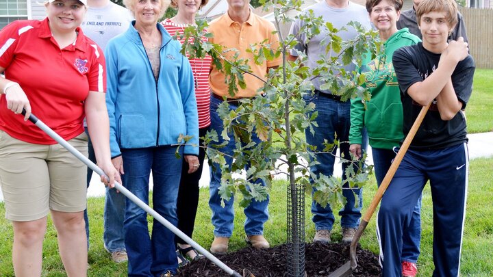 Tree planters standing by a recently planted oak tree. 