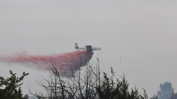 Photo of a single engine air tanker providing a retardant drop over a fire