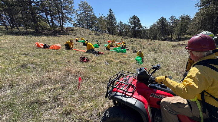 This is a photo of an instructor at Spring Wildland Fire Academy overseeing students deploy a fire shelter