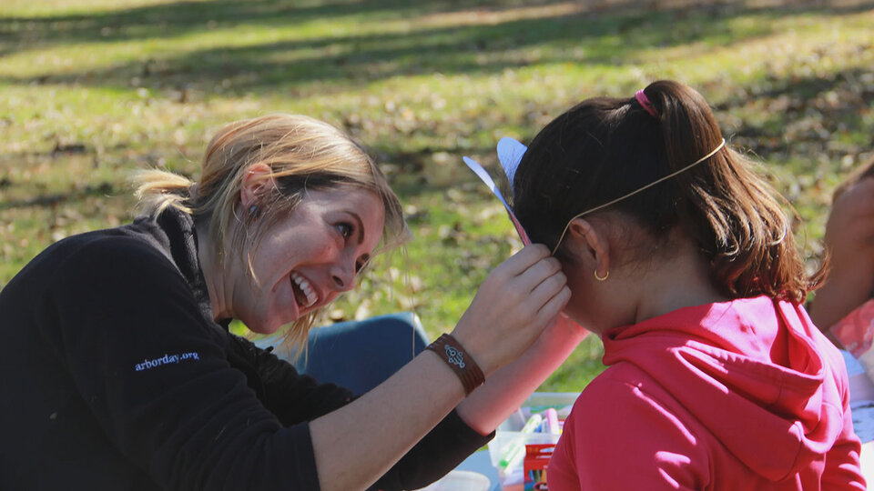 A NFS employee helps a child adjust their paper mask.