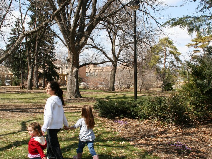 A photo of a mother and her children walking past trees