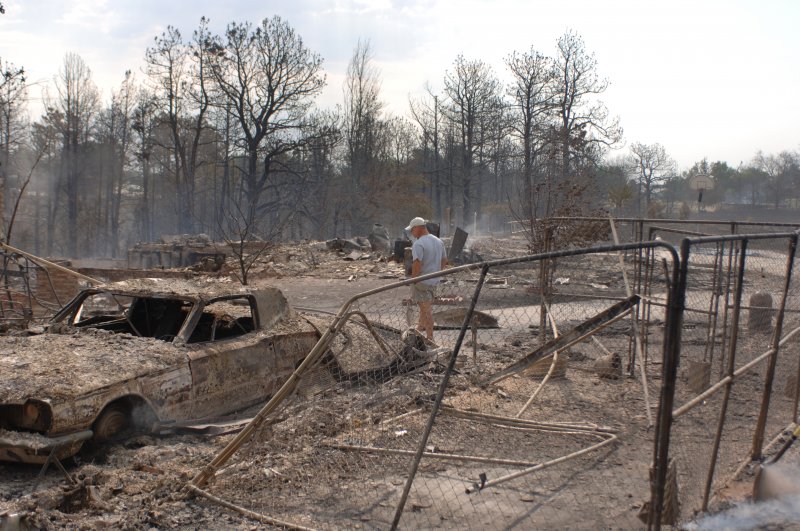 Homeowner walks through the aftermath of a wildfire. 